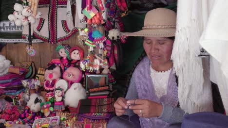 medium shot of traditional woman (cholita) weaving in the recoleta market, sucre