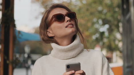 caucasian female in sunglasses using smartphone outdoors.