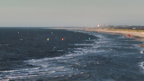 aerial view showing group of kite surfer with colorful kites in north sea at hoek van holland beach at sunset - netherlands,europe