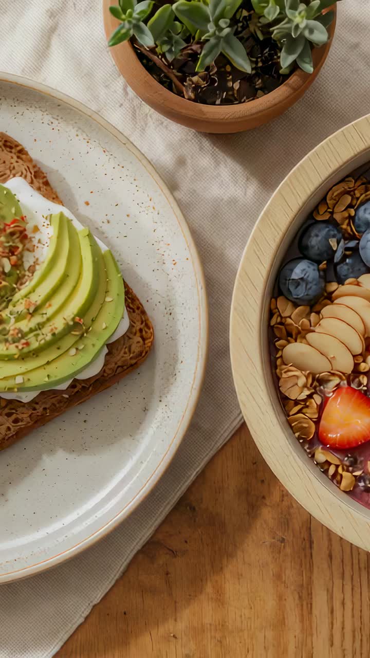 Vertikal video: Klipset starter med å panorere kameraet over et trebord som viser avokadotoast, granola og sukkulent