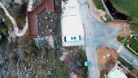 A-rising-drone-shot-above-a-white-camper-van-modified-for-nomadic-living,-remote-work-and-adventure-travel-sits-parked-at-an-overlook