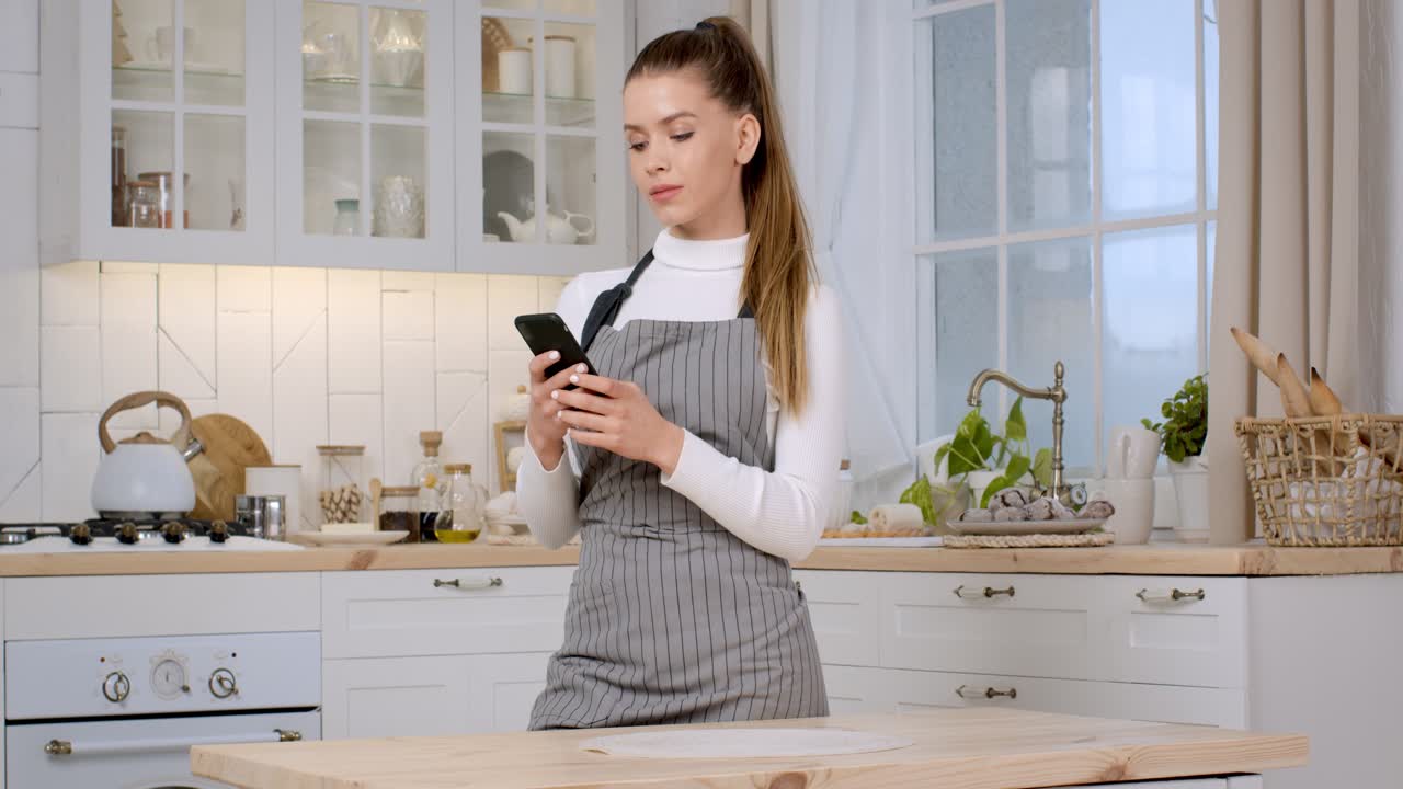 mujer en una cocina usando un teléfono inteligente