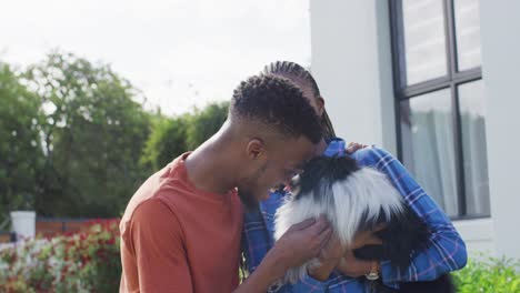 Happy-african-american-couple-petting-dog-in-backyard