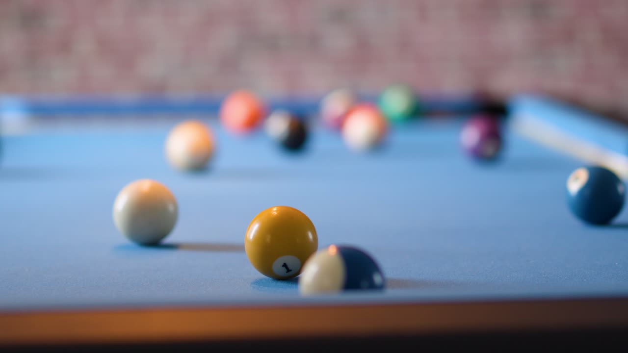 Player aims cue stick for break shot on blue pool table, shallow depth of field