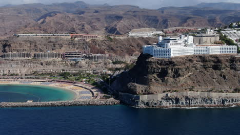 Orbital-aerial-view-of-Amadores-beach,-the-mountains-and-the-resorts-near-the-coast