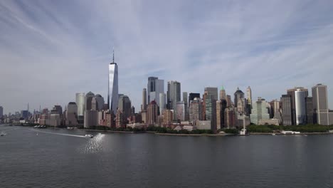 Aerial-view-of-boats-on-Hudson-river,-in-front-of-Battery-park-city,-in-sunny-New-York,-USA---low,-tracking,-drone-shot