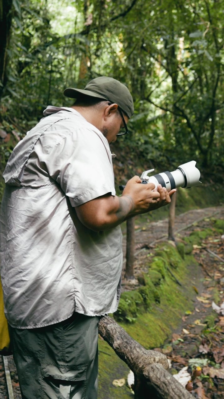 Fotografo che usa un teleobiettivo in una lussureggiante foresta tropicale