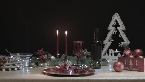 man places a red glass on a decorated christmas table in a dark room