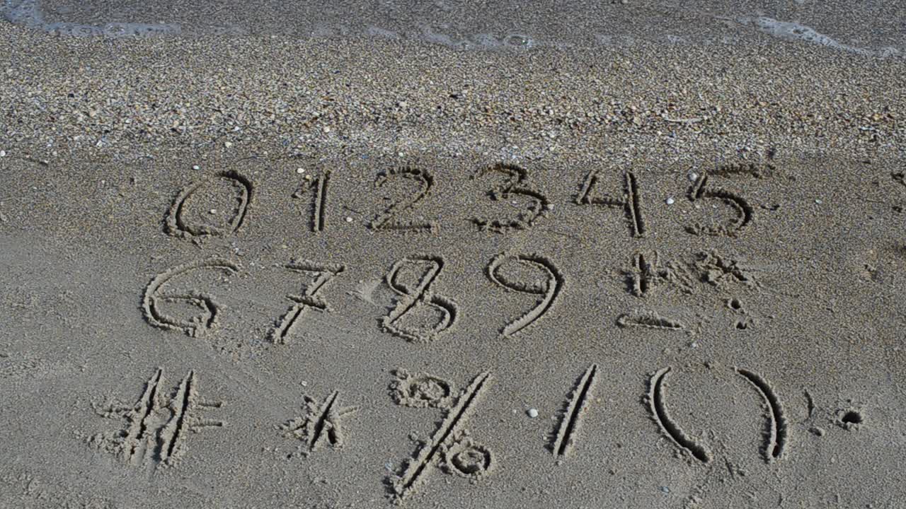 Cijfers en tekens geschreven in strandzand. Strandopname.
