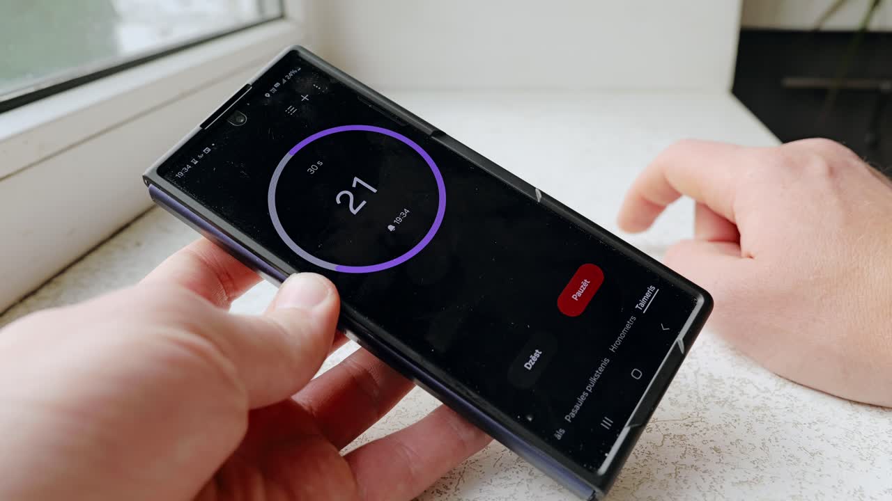 Man taps fingers on windowsill as smartphone timer counts down thirty seconds