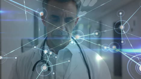 Animation-of-network-of-connections-over-caucasian-male-doctor-using-tablet