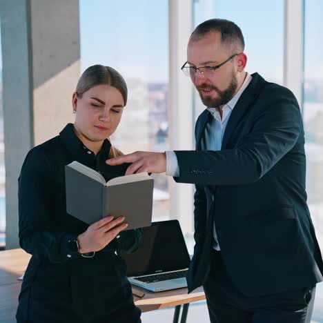 businessman and secretary in office. young woman with notebook talking with her boss in the light office with panoramic windows view on the city
