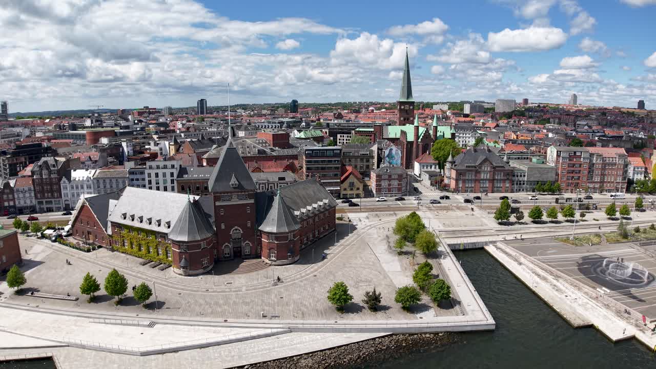 Aerial drone footage of historic waterfront buildings and canals in Aarhus, Denmark on a bright sunny day with scattered clouds
