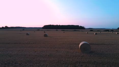 flying above the field with hay rolls sunrise.