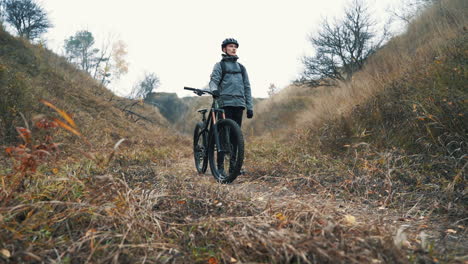 谷の真ん中でマウンテン バイクを持つ男性サイクリスト