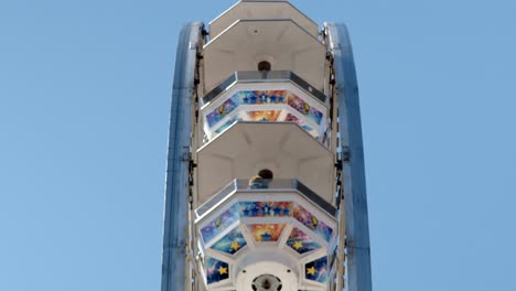 a blue and white ferris wheel spinning down against a blue sky at a fair