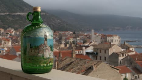 botella de vino tradicional en el balcón con vista a la ciudad vieja, las montañas y el mar