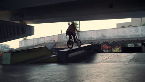 extreme teenage man falling down while practicing jump stunt on bicycle at park.