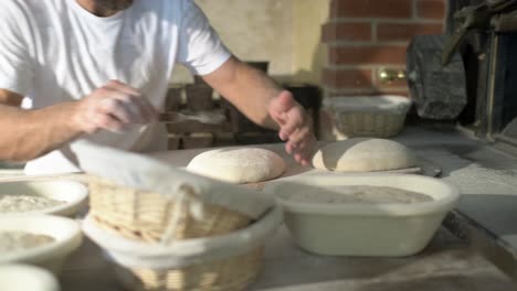 side shot, a baker flouring, cuting and puting bread loaf in a traditional stone oven, using baker’s peel