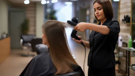 hairstylist blow-drying client's hair in a salon