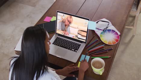 Profesora-Caucásica-Usando-Una-Computadora-Portátil-En-Una-Videollamada-Con-Una-Estudiante,-Tomando-Notas