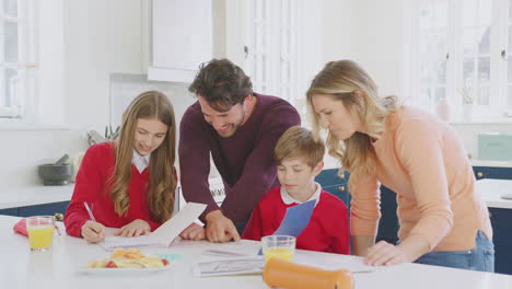 parents helping children in school uniform doing homework at kitchen counter