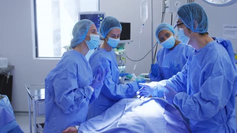 Diverse-surgeons-wearing-surgical-caps-and-face-masks-in-operating-theatre