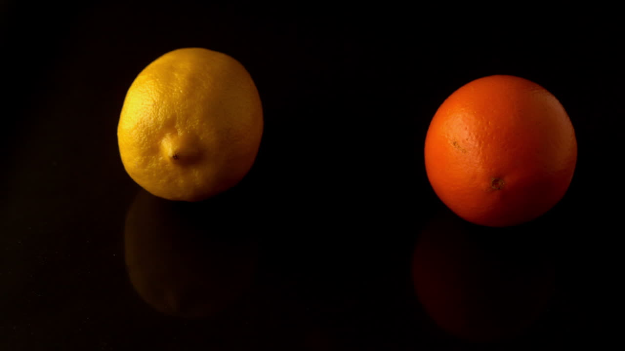 Citron og appelsin, der snurrer på sort overflade