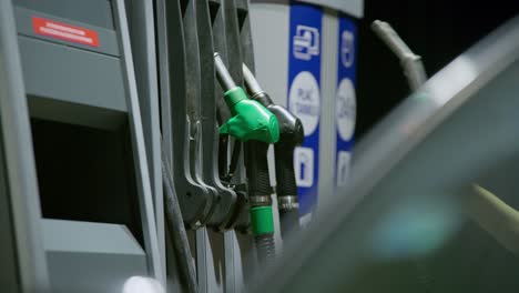 Person-picks-up-fuel-handle-to-begin-refueling-car's-tank-on-a-petrol-station