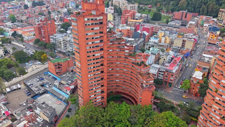 Riprese aeree con drone che si alzano dalla base alla cima di una torre del Torres del Parque a Bogotá, mostrando la sua iconica forma a spirale e il design modernista accanto alla storica Plaza de Toros di La Santamaría.