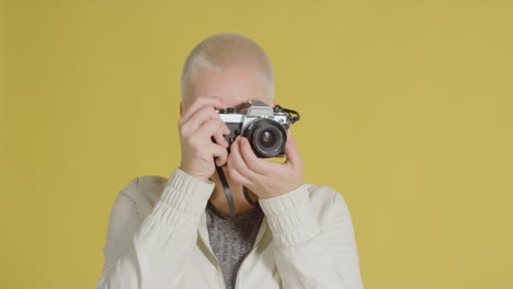 modelo caucásica femenina posando con slr vintage contra fondo amarillo 03