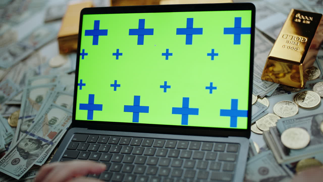 Laptop surrounded by money and gold bars