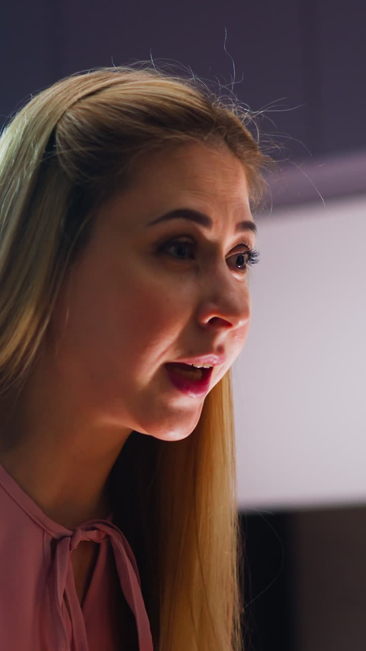 충격에 빠진 긴 머리 여성은 테이블에서 일어서서 집에서 현대적인 부에서 저녁 식사에서 파트너를 학대하는 분노로 이야기합니다.