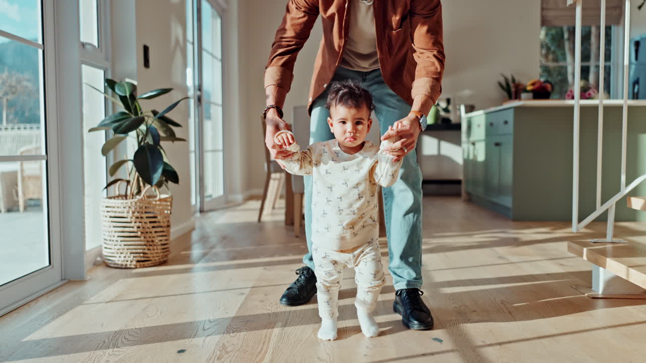 Father helping baby with first steps at home