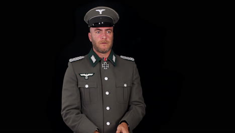 german second world war wehrmacht army officer in grey uniform cocking and pointing p38 pistol gun with black background