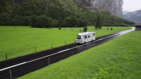 White-camper-drives-through-green-countryside-in-Switzerland