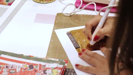 woman writing on gold foil paper, making creative crafts for christmas