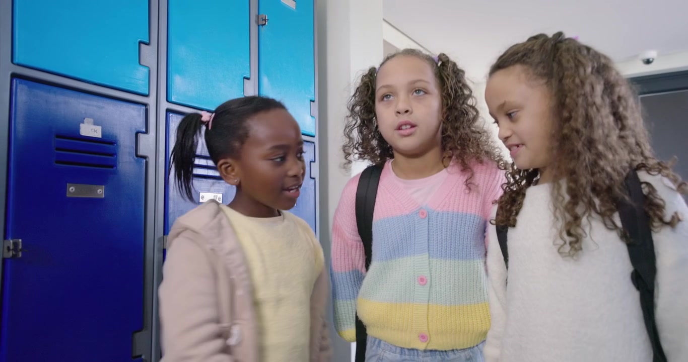 African American teens meeting at blue lockers, pink coat girl arriving, placing backpack for class