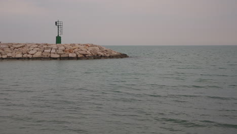 Calm-sea-and-small-stone-breakwater,-the-entrance-to-Rodi-Garganico-marina-Italy