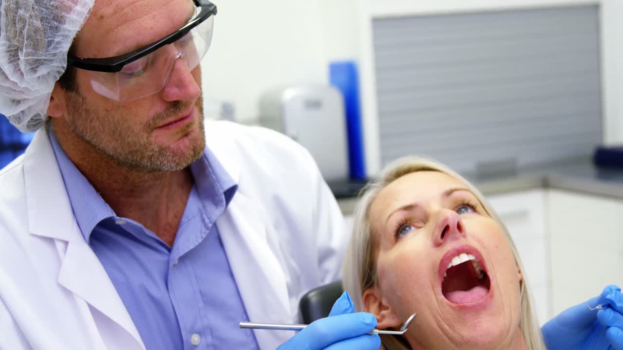 Dentist examining a female patient with dental tools