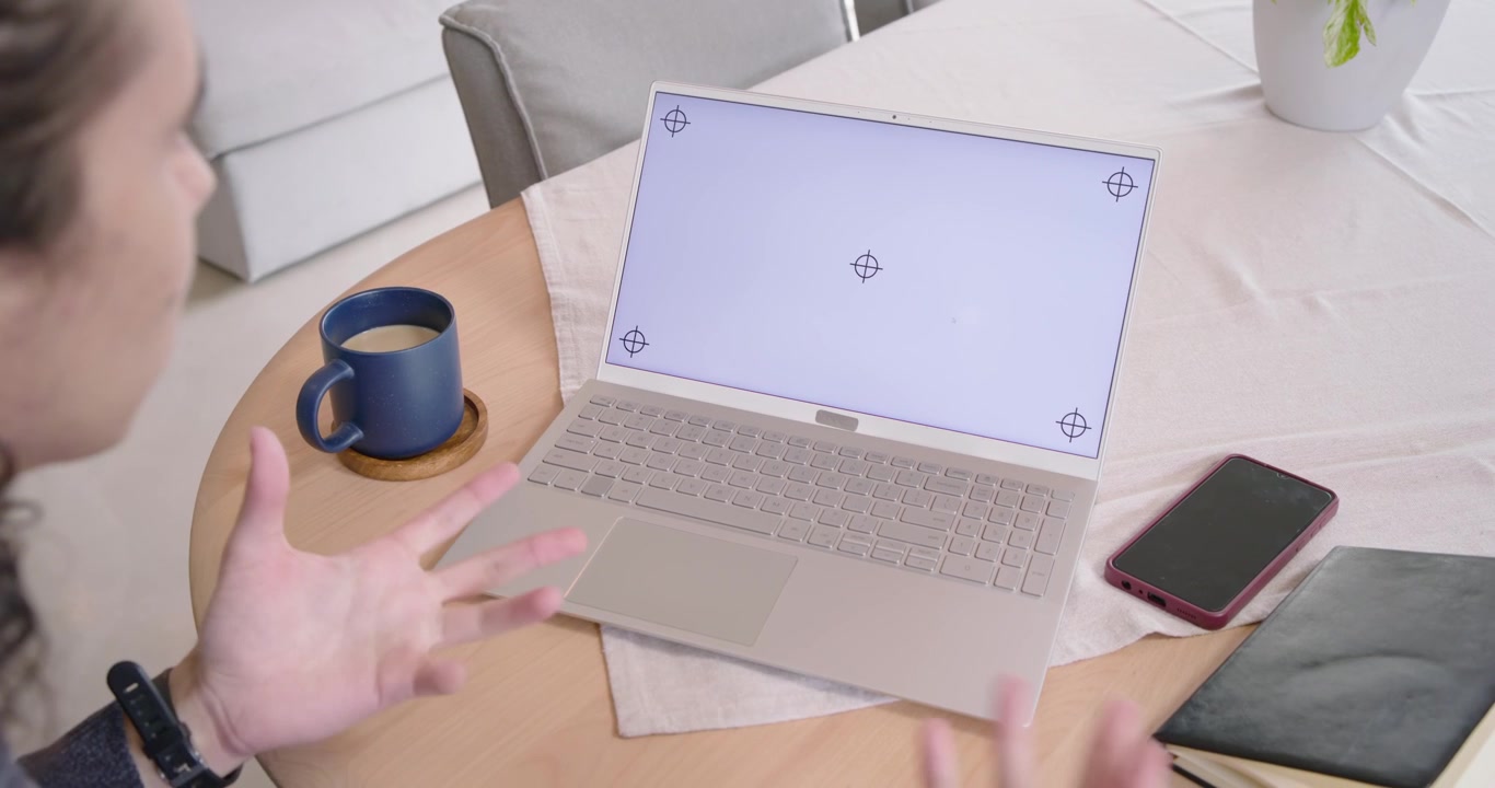 Uomo seduto a un tavolo di legno, sollecitato dallo schermo di test del laptop, che gesticola e si sporge in avanti.