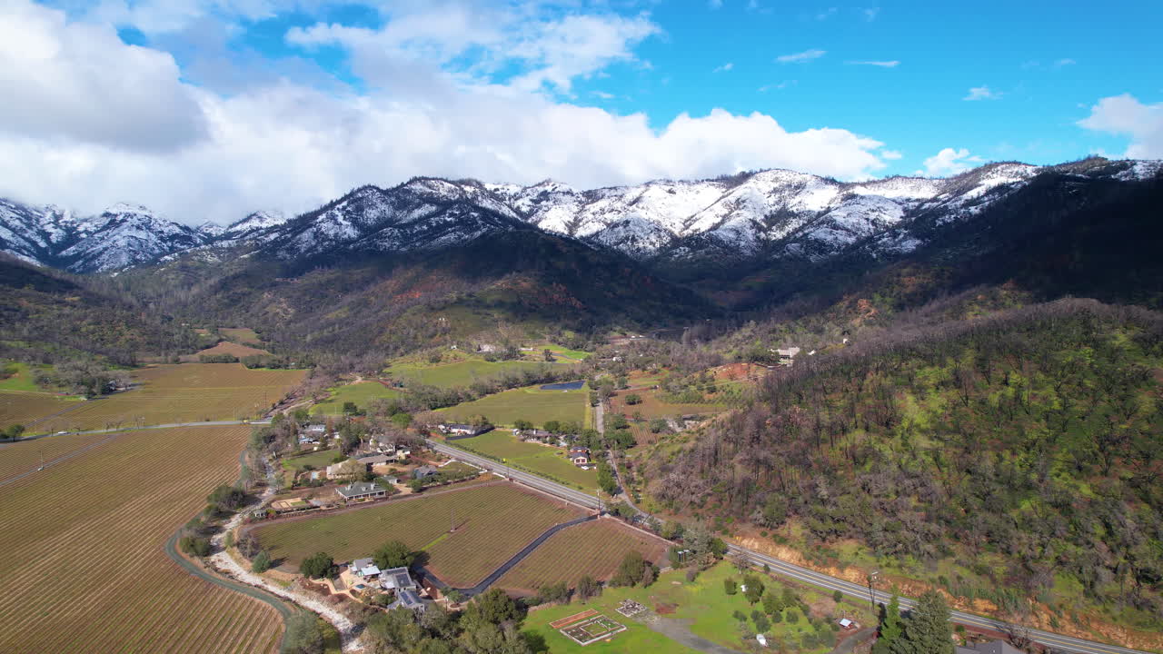 retiro aéreo volando sobre los viñedos del valle de napa y mostrando las montañas blancas de nieve
