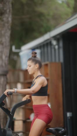 young woman exercising on an air bike outdoors