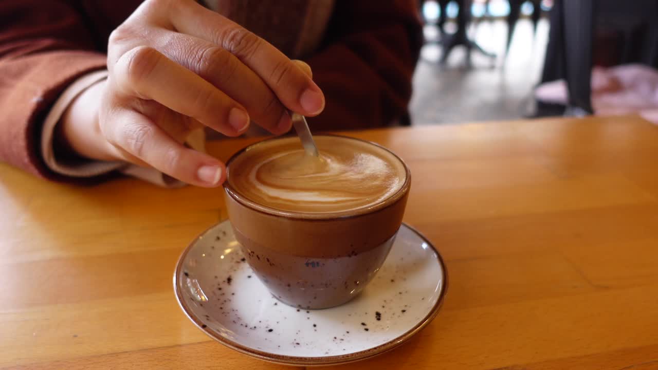 mujer mezclando un latte en una cafetería