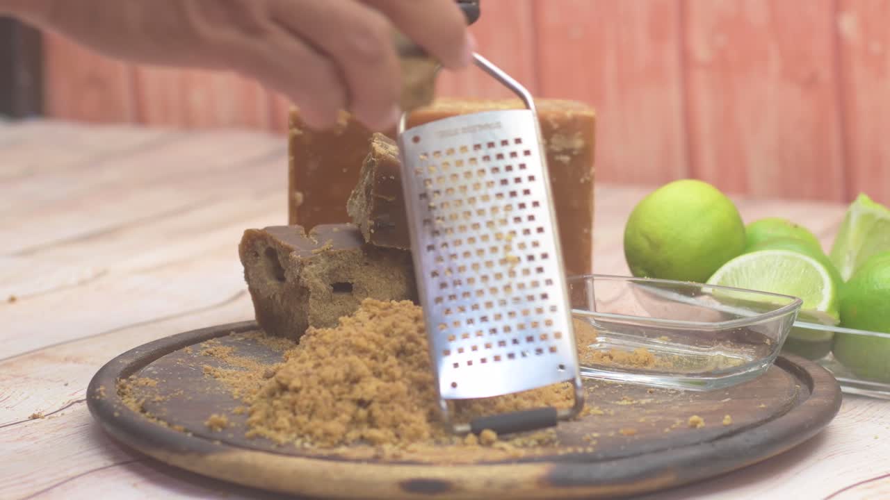 Uomo che grattugia zucchero di canna panela tradizionale in cucina