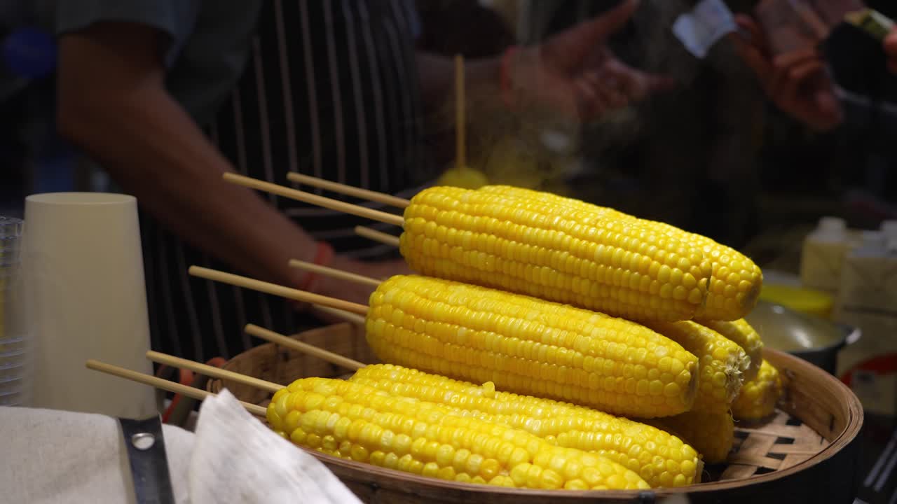 Fresh corn on the cob displayed on skewers at a street food vendor stall