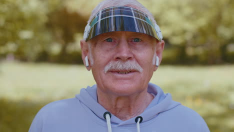 portrait of athletic senior sport runner man wearing earphones listening music, smiling, cardio