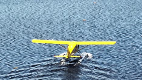 aerial view follows yellow beaver airplane cruising through calm waters