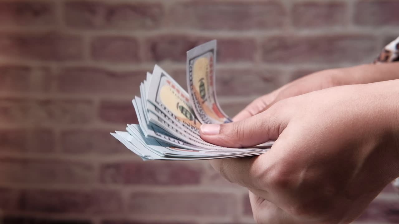 manos sosteniéndonos billetes de un dólar