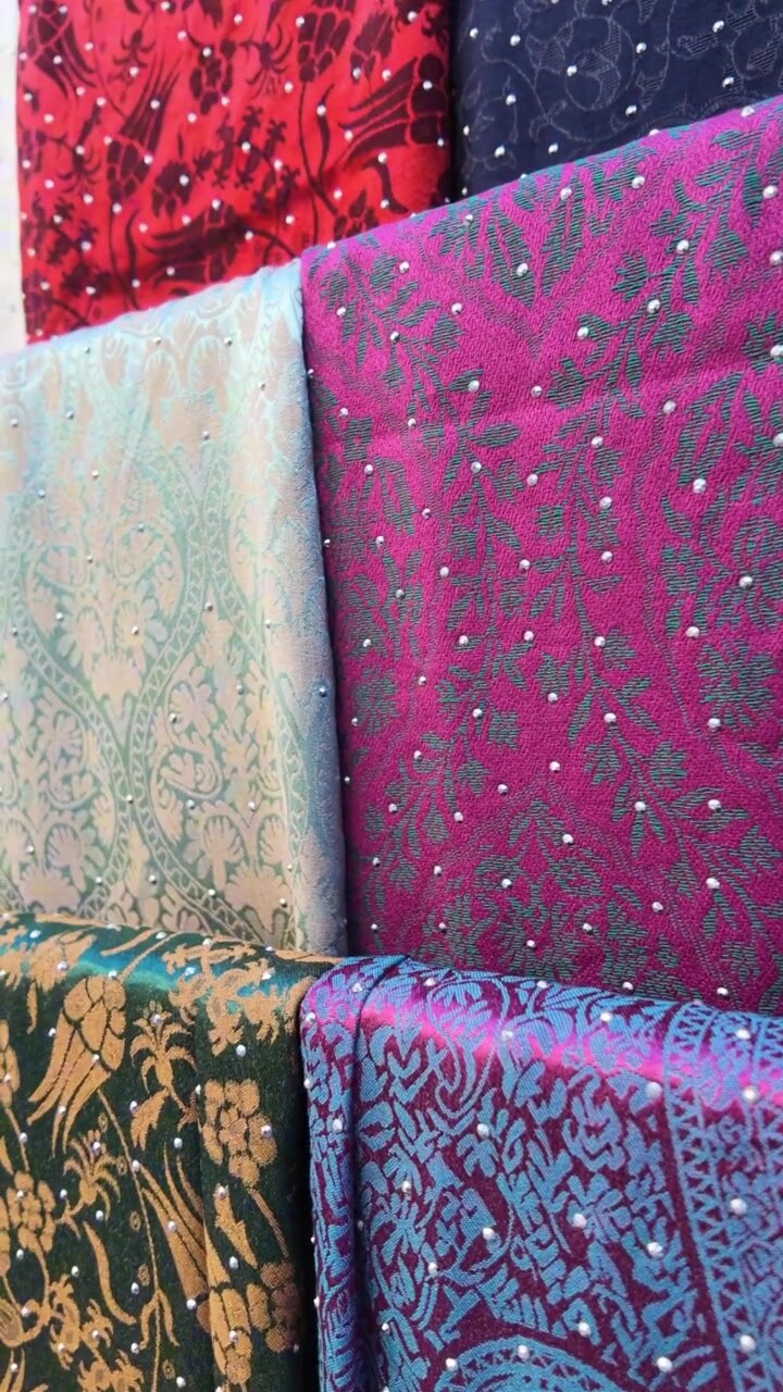 Rotoli di tessuto colorati con motivi intricati e decorazioni in strass